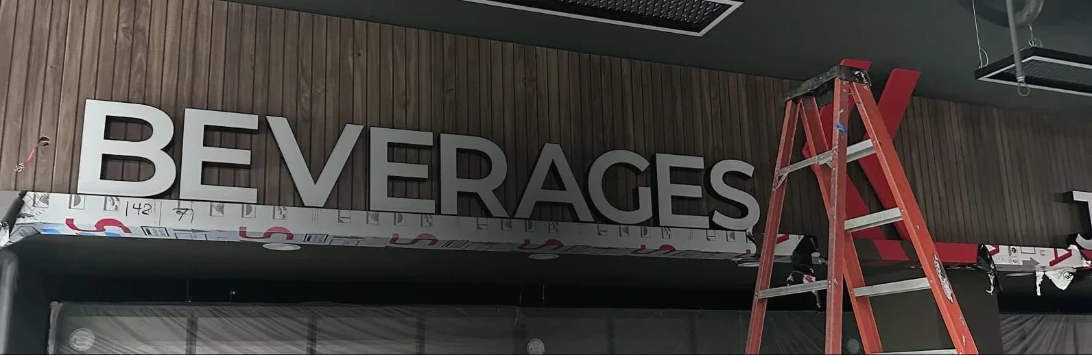 Store signage installation: large BEVERAGES letters on a wood-slat wall
